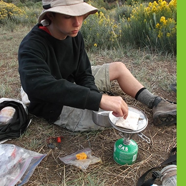 Aspiro student cooking in the wilderness using a gas burner