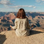 A girl meditates in front of the grand canyon as a way of illustrating how to combat Anxiety in Teens | Aspiro Wilderness Therapy Program for Teens